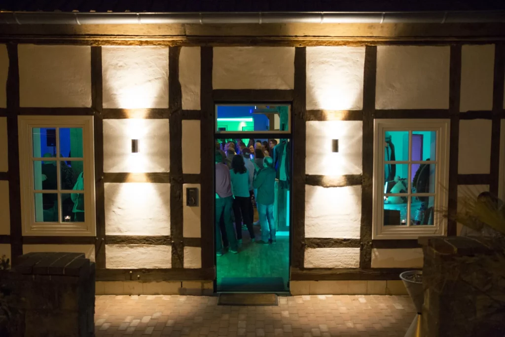 Blick bei Nacht in den beleuchteten Innenraum, in dem Menschen tanzen.