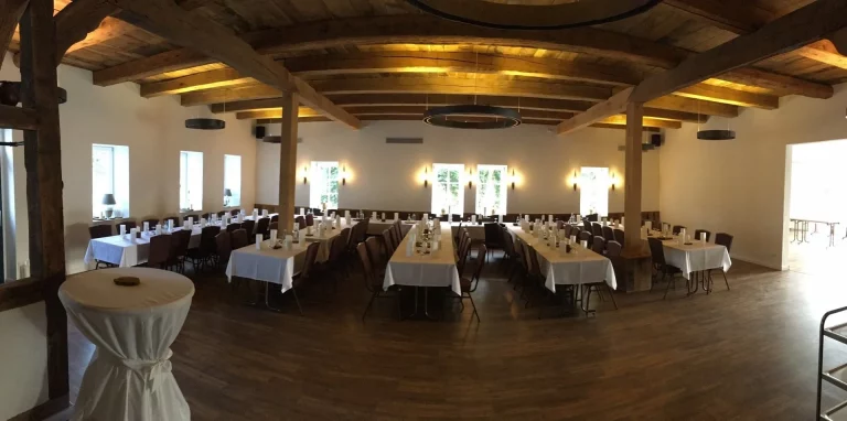 Die Eventlocation ist festlich mit weißen Tischdecken vorbereitet.